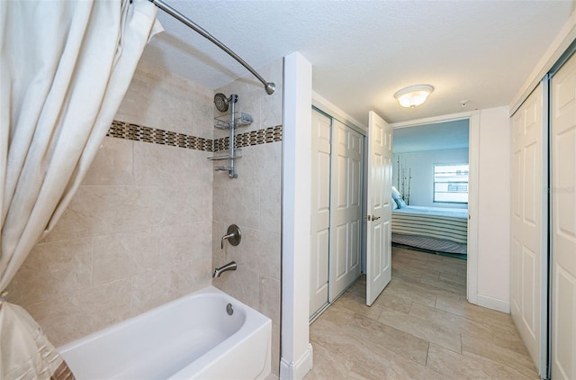 ensuite bathroom featuring a textured ceiling, shower / bath combo with shower curtain, ensuite bath, and baseboards