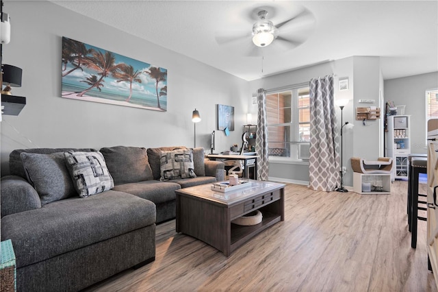 living room with wood finished floors, a ceiling fan, and baseboards