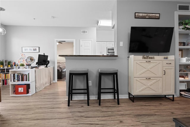 kitchen with a breakfast bar area, visible vents, and light wood-type flooring