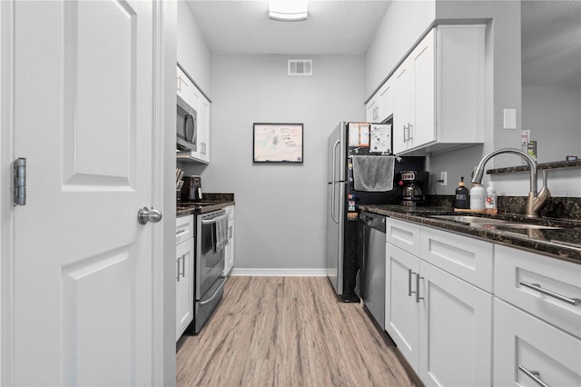 kitchen featuring a sink, light wood-style floors, appliances with stainless steel finishes, white cabinetry, and visible vents