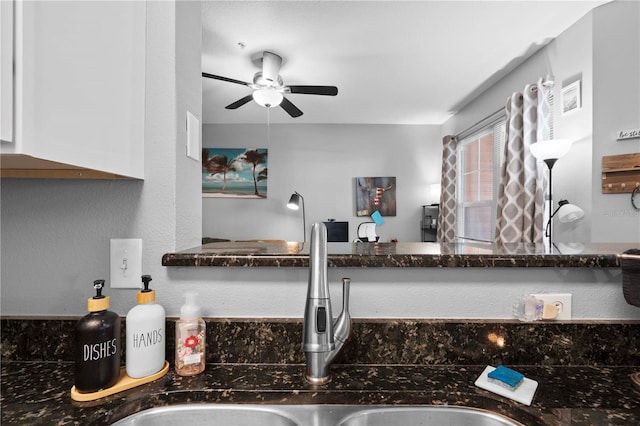 details featuring a ceiling fan, dark stone counters, white cabinetry, and a sink