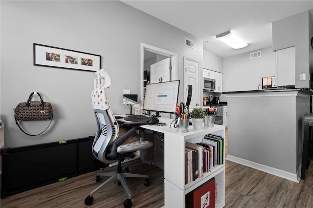 office featuring visible vents, baseboards, and wood finished floors