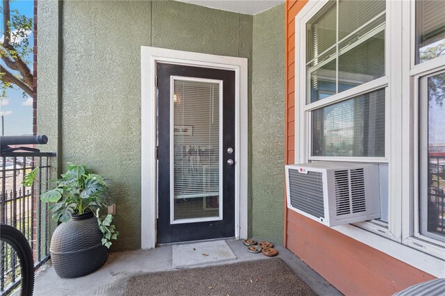 property entrance with cooling unit, a balcony, and stucco siding