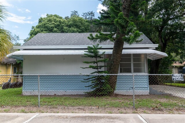 view of side of home with a shingled roof and fence