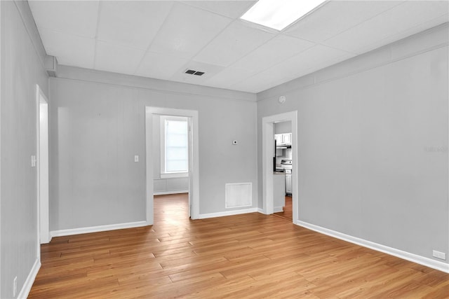 unfurnished room featuring visible vents, light wood finished floors, baseboards, and a paneled ceiling