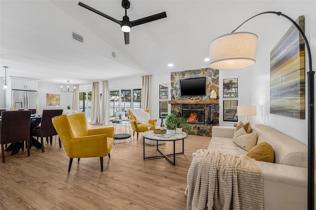 12641 98th St, Largo, FL 33773 - living area featuring ceiling fan with notable chandelier, light wood-style flooring, a stone fireplace, visible vents, and lofted ceiling
