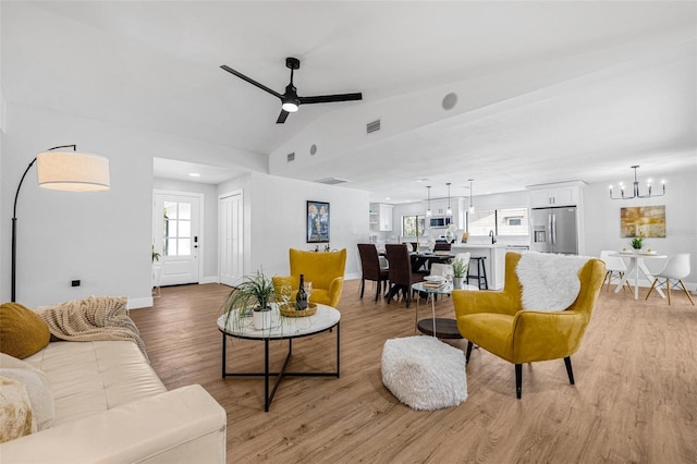12641 98th St, Largo, FL 33773 - living room featuring baseboards, vaulted ceiling, visible vents, light wood finished floors, and ceiling fan with notable chandelier