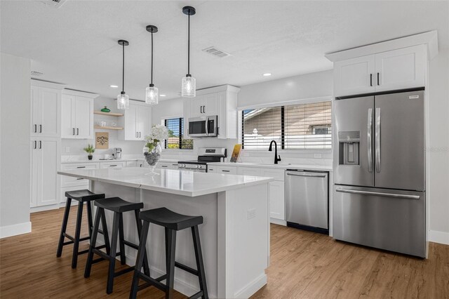 12641 98th St, Largo, FL 33773 - kitchen with visible vents, a center island, light countertops, light wood-type flooring, and stainless steel appliances