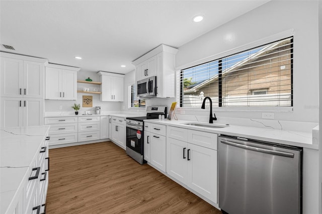 12641 98th St, Largo, FL 33773 - kitchen with light wood-type flooring, open shelves, visible vents, appliances with stainless steel finishes, and a sink