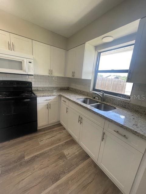 kitchen with white microwave, black electric range, a sink, and white cabinetry