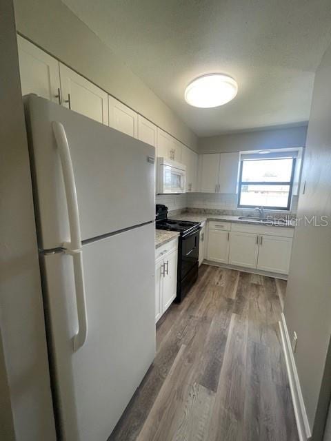 kitchen featuring a sink, white appliances, white cabinetry, wood finished floors, and backsplash