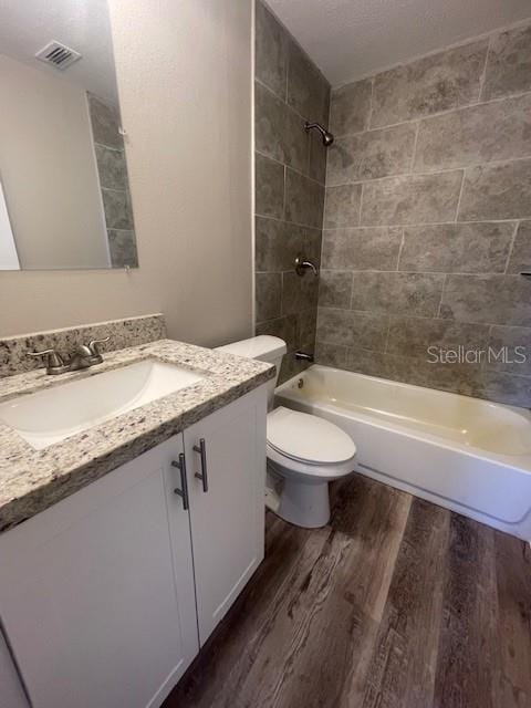bathroom featuring shower / bathtub combination, vanity, visible vents, toilet, and wood finished floors