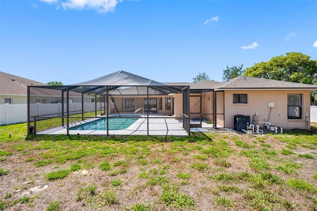 back of house featuring a fenced backyard, glass enclosure, a patio, stucco siding, and a fenced in pool