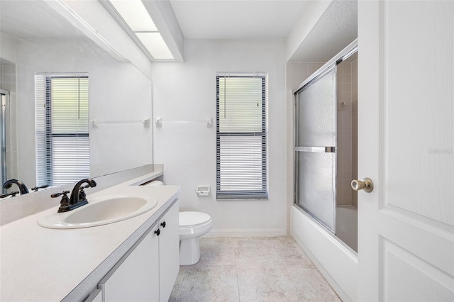 full bathroom with shower / bath combination with glass door, vanity, baseboards, tile patterned flooring, and toilet