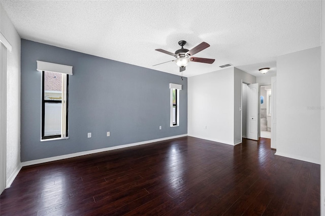 empty room with visible vents, a ceiling fan, wood finished floors, and a textured ceiling