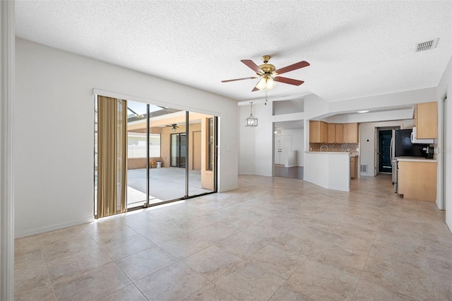 unfurnished living room featuring a textured ceiling, a ceiling fan, and visible vents