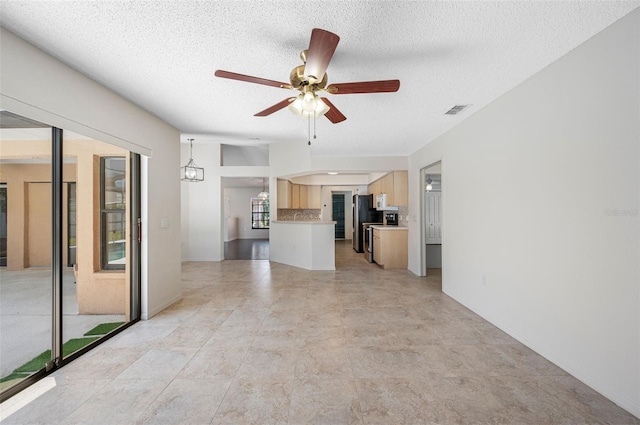 unfurnished living room featuring visible vents, a textured ceiling, and ceiling fan with notable chandelier