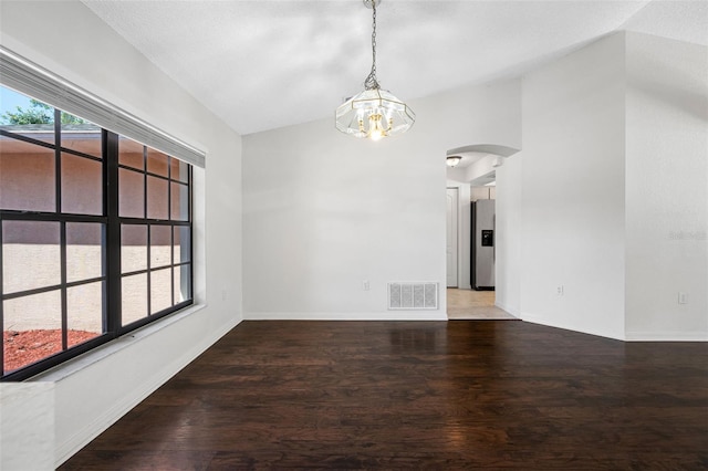 unfurnished dining area featuring arched walkways, wood finished floors, vaulted ceiling, and visible vents