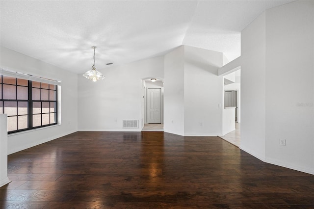empty room with visible vents, baseboards, arched walkways, and wood finished floors