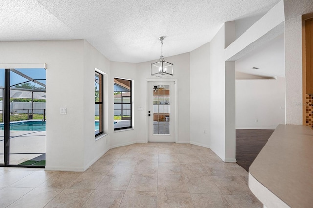 unfurnished dining area with a textured ceiling, light tile patterned floors, and baseboards