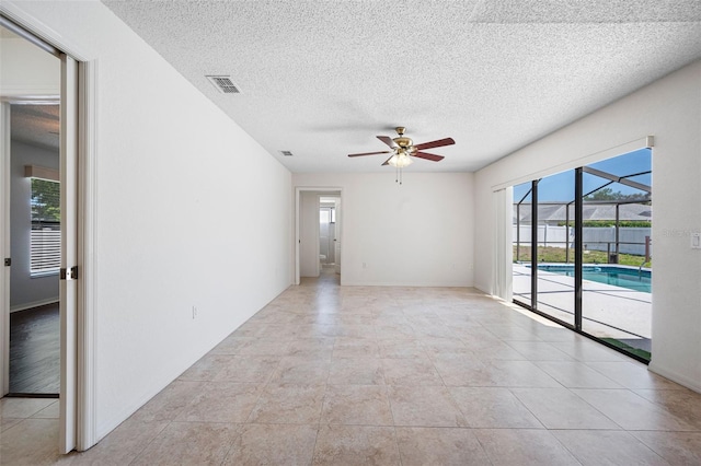 spare room featuring visible vents, baseboards, light tile patterned floors, a ceiling fan, and a textured ceiling
