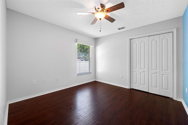 unfurnished bedroom featuring visible vents, a closet, ceiling fan, a textured ceiling, and wood finished floors