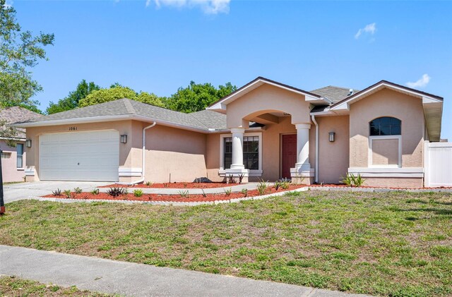ranch-style home with an attached garage, driveway, stucco siding, and a front lawn