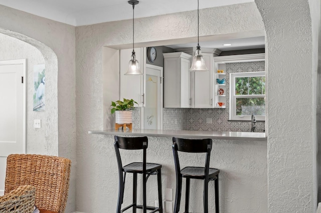 636 16th Ave NE, Saint Petersburg, FL 33704 - kitchen featuring a kitchen bar, arched walkways, a textured wall, and decorative backsplash