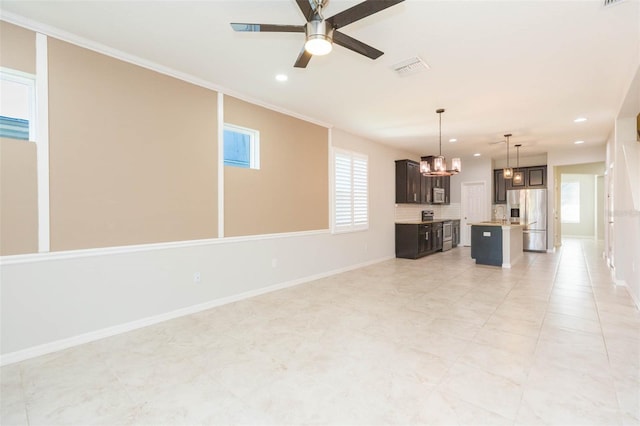 unfurnished living room with ceiling fan with notable chandelier, baseboards, visible vents, and recessed lighting
