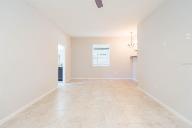 unfurnished room featuring ceiling fan with notable chandelier and baseboards
