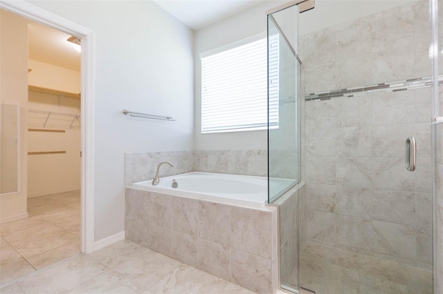 full bath with a bath, a spacious closet, and a shower stall