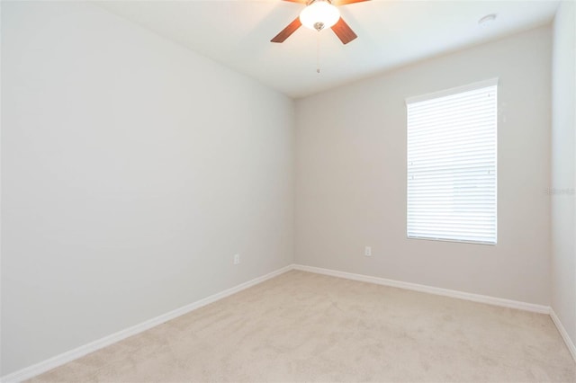 empty room featuring light colored carpet, baseboards, and a ceiling fan