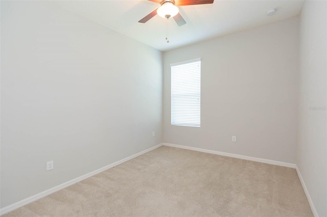 unfurnished room featuring light colored carpet, baseboards, and a ceiling fan