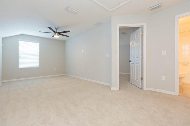 spare room with light carpet, ceiling fan, vaulted ceiling, and visible vents