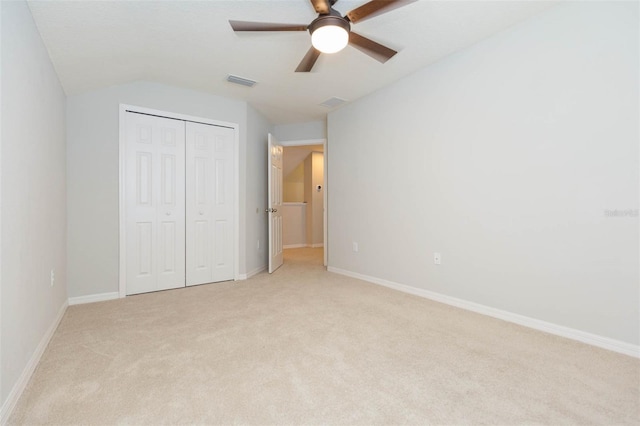 unfurnished bedroom with a closet, light colored carpet, vaulted ceiling, visible vents, and baseboards