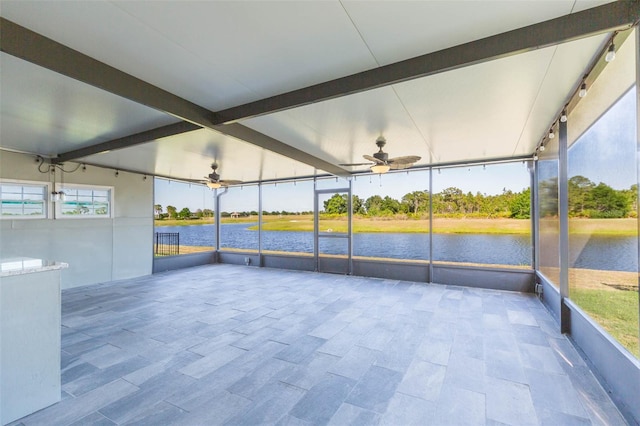 unfurnished sunroom with a water view, beamed ceiling, and ceiling fan