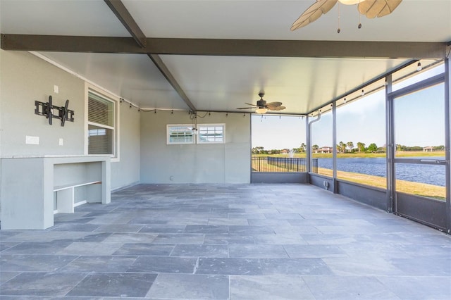 unfurnished sunroom featuring a water view, beamed ceiling, and a ceiling fan