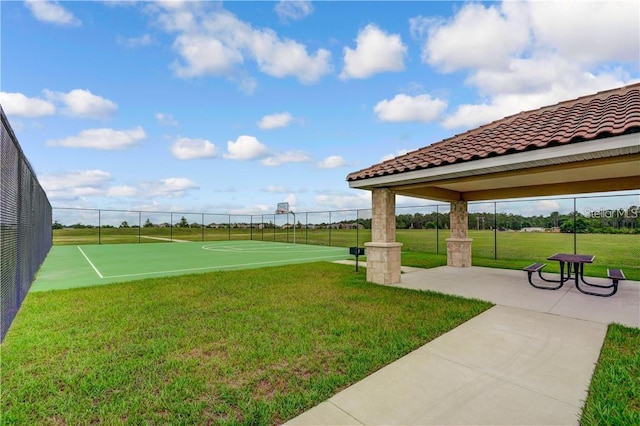 view of home's community with community basketball court, fence, and a lawn