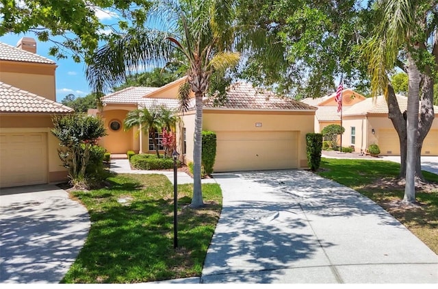 mediterranean / spanish home featuring stucco siding, driveway, a front yard, a garage, and a tiled roof