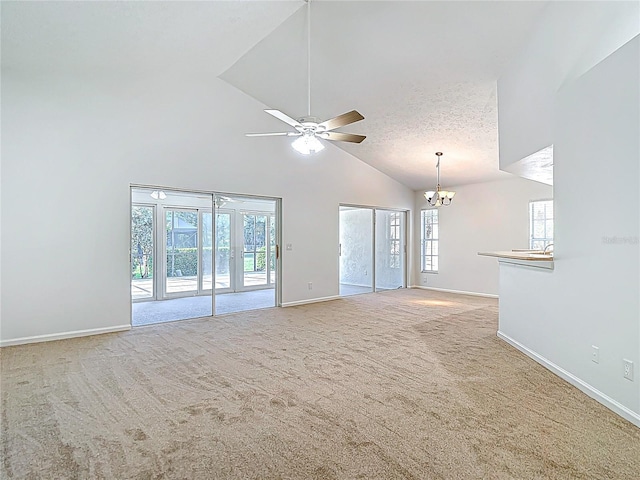 unfurnished living room with ceiling fan with notable chandelier, carpet flooring, and a healthy amount of sunlight