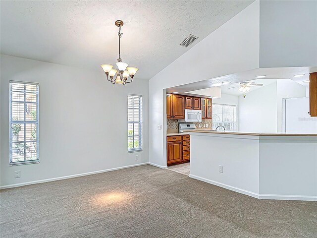 kitchen with white appliances, a textured ceiling, light colored carpet, visible vents, and lofted ceiling