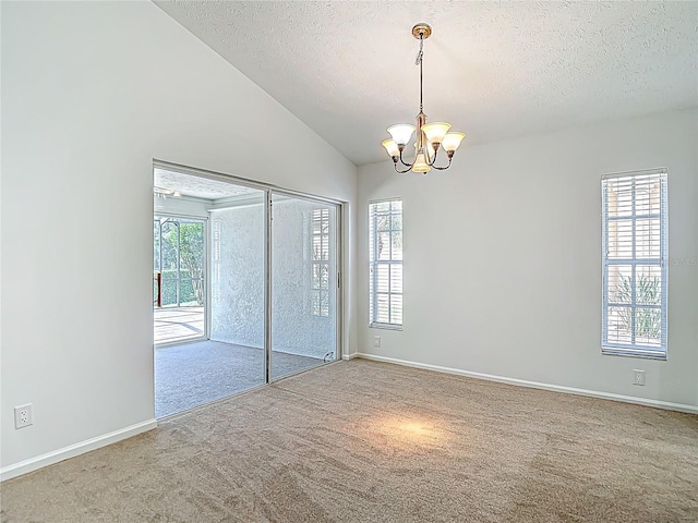 unfurnished room featuring a textured ceiling, carpet flooring, a notable chandelier, and vaulted ceiling