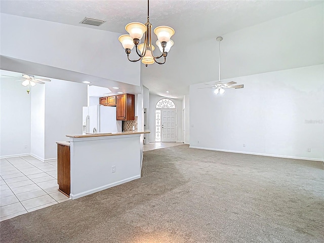 kitchen with ceiling fan with notable chandelier, brown cabinetry, white refrigerator with ice dispenser, visible vents, and baseboards