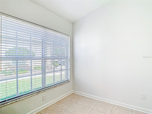 empty room featuring light tile patterned flooring and baseboards