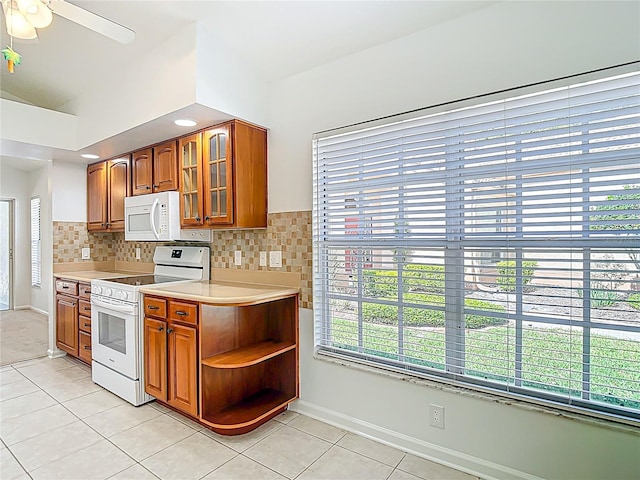 kitchen featuring brown cabinetry, light tile patterned floors, light countertops, and white appliances