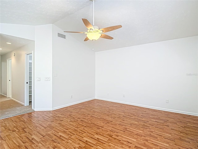 empty room with light wood-style flooring, ceiling fan, lofted ceiling, and visible vents