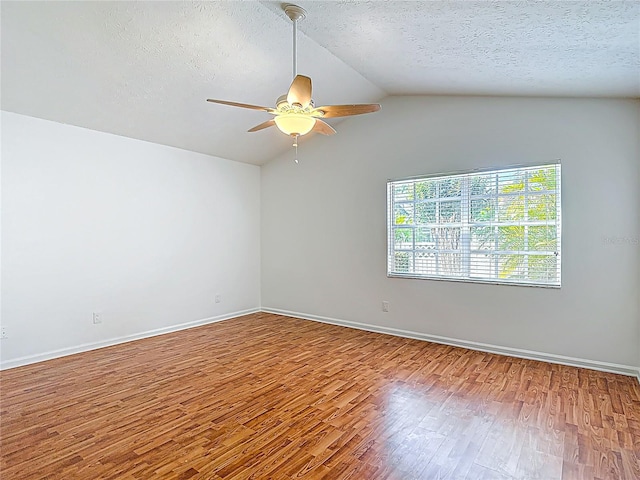 empty room with lofted ceiling, a textured ceiling, wood finished floors, and ceiling fan