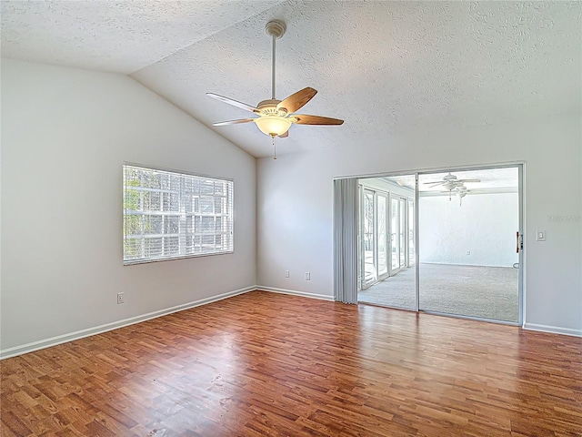 unfurnished bedroom with ceiling fan, a textured ceiling, vaulted ceiling, wood finished floors, and baseboards