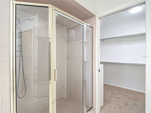 bathroom with a spacious closet, a stall shower, and a textured ceiling