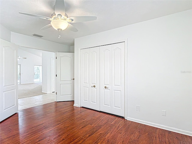 unfurnished bedroom featuring baseboards, wood finished floors, a closet, and visible vents